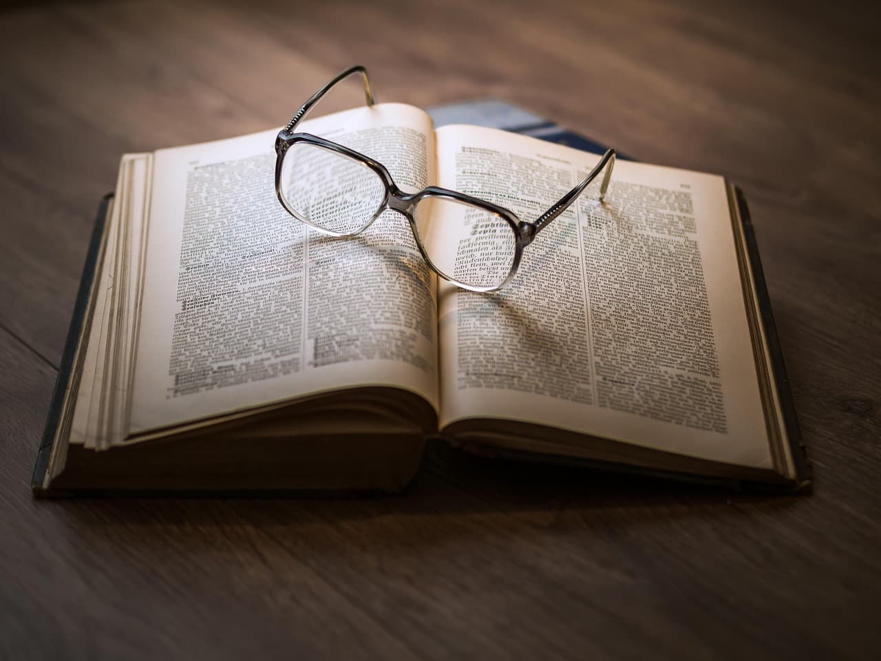 An open book with reading glasses resting on the pages, representing short stories in Spanish organized by difficulty level