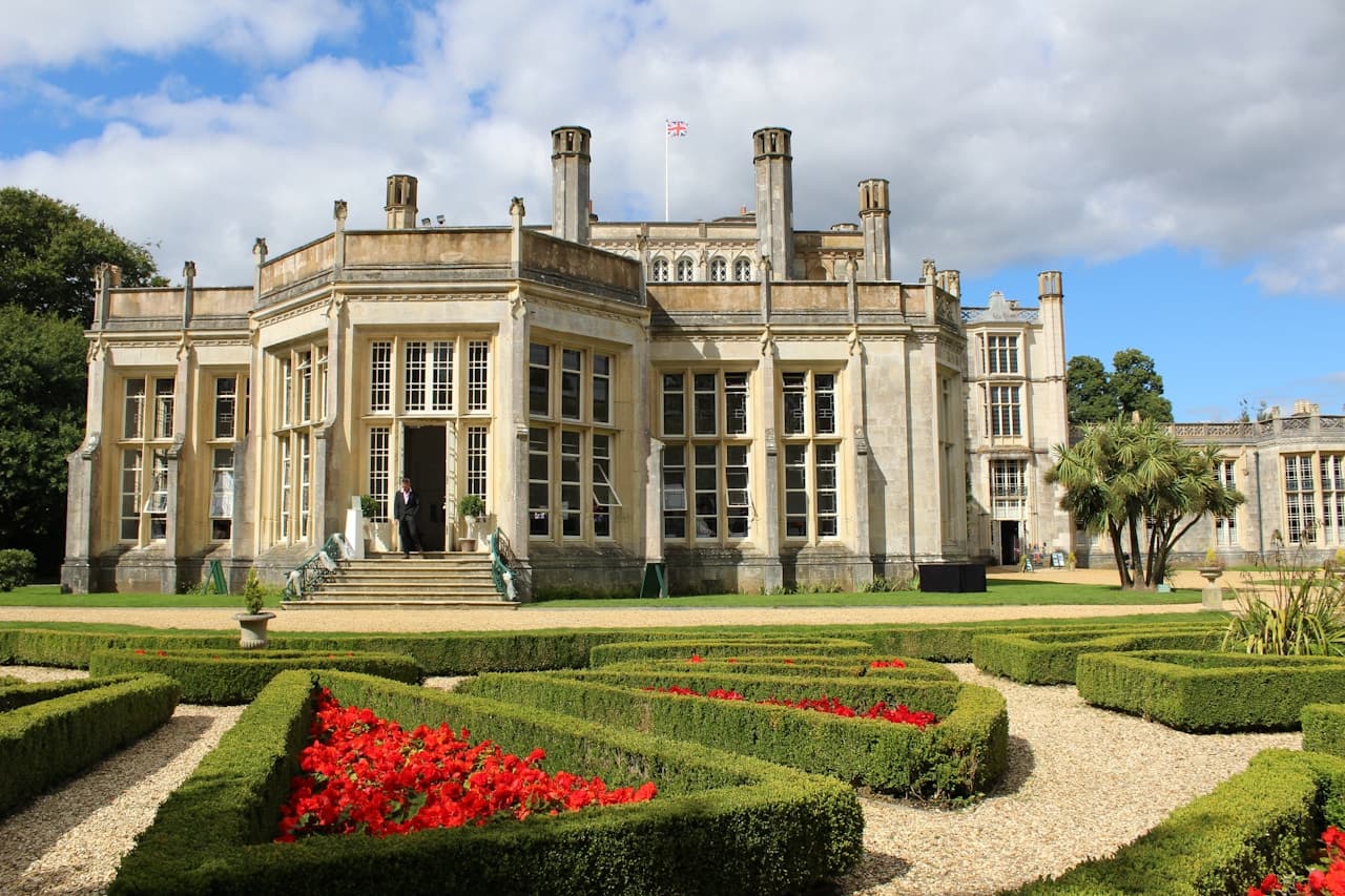 English country manor house surrounded by green gardens, evoking the Regency-era estates of Pride and Prejudice