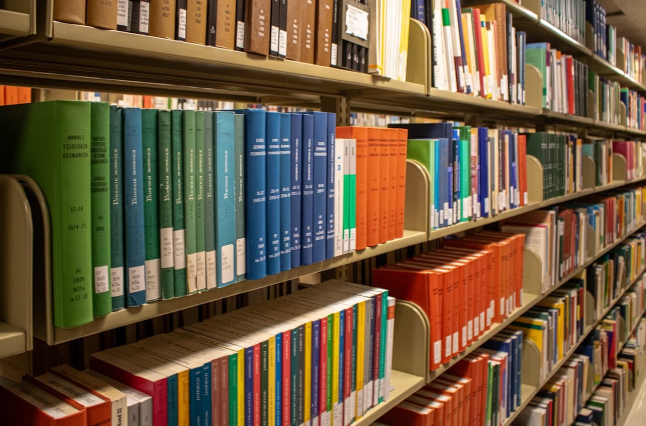 A stack of colorful paperback books on a wooden table beside a coffee cup, representing graded readers for adult Spanish learners